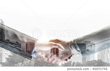 Business handshake as idea for unity and cooperation or greeting. Mixed media Business handshake as idea for unity and cooperation or greeting. Mixed media 60055748