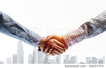 Business handshake as idea for unity and cooperation or greeting. Mixed media Business handshake as idea for unity and cooperation or greeting. Mixed media 60055754