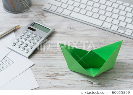 Modern office workspace with green paper ship Modern office workspace with green paper ship 60055809