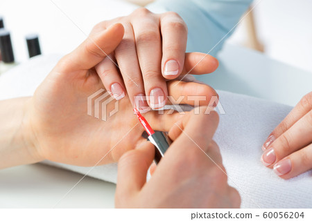 Woman receiving manicure by nail beautician Woman receiving manicure by nail beautician 60056204