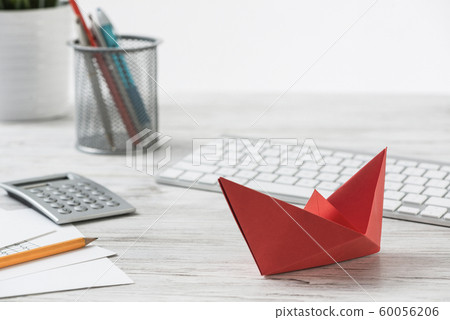 Businessman workspace at desk with red paper ship Businessman workspace at desk with red paper ship 60056206