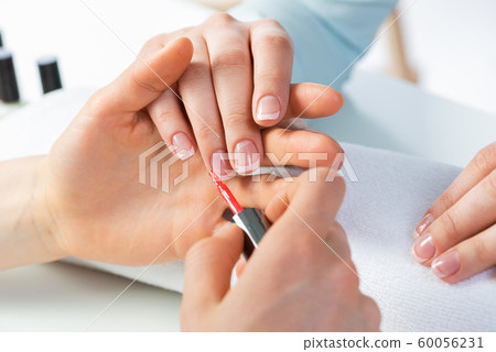 Woman receiving manicure by nail beautician Woman receiving manicure by nail beautician 60056231