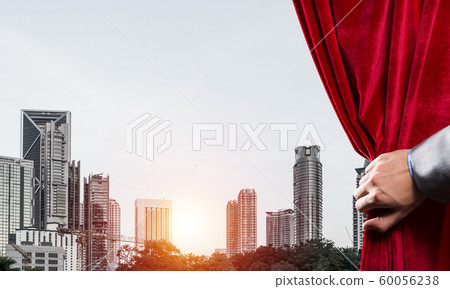 Modern business cityscape behind curtain opened by businessman hand Modern business cityscape behind curtain opened by businessman hand 60056238