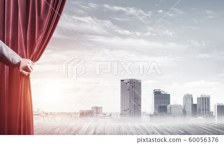 Business city in gray fog behind red curtain and hand holding it Business city in gray fog behind red curtain and hand holding it 60056376