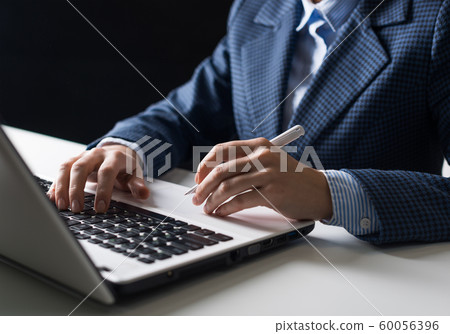 Man in business suit sitting at desk with laptop 60056396