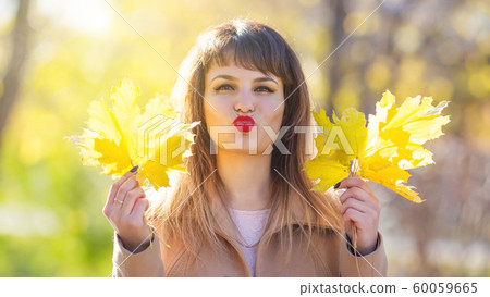A brunette woman with an armful of leaves in her A brunette woman with an armful of leaves in her 60059665