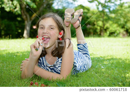 pretty teenage girl outdoors with cherry 60061718