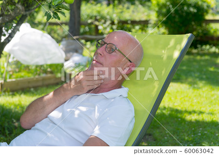 Senior man relaxing in the deckchair in his garden 60063042