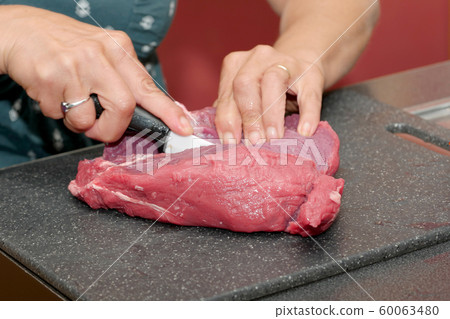 Woman's hands cutting meat 60063480