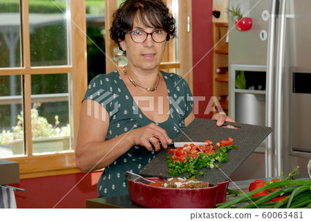 smiling middle-aged brunette woman preparing meal smiling middle-aged brunette woman preparing meal 60063481