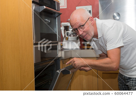 Mature handsome man cooking in home kitchen Mature handsome man cooking in home kitchen 60064477