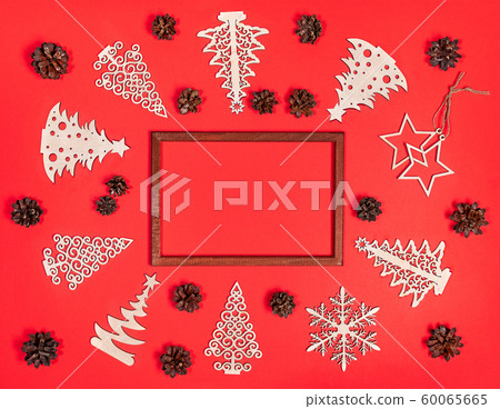 Festive christmas mockup on red background with brown photo frame in center and diy wooden decorations and pine cones around it. Creative xmas arrangement. Flat lay, top view, copy space. Festive christmas mockup on red background with brown photo frame in center and diy wooden decorations and pine cones around it. Creative xmas arrangement. Flat lay, top view, copy space. 60065665