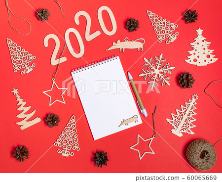Creative festive christmas mockup on red background with diy handmade wooden xmas decorations, numbers 2020, rat, cones and copy space for text on white notepad. Flat lay, top view, copy space. Creative festive christmas mockup on red background with diy handmade wooden xmas decorations, numbers 2020, rat, cones and copy space for text on white notepad. Flat lay, top view, copy space. 60065669