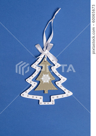 Xmas decorations. Christmas toy white with olive carved wooden Christmas tree on blue background. Top view. Xmas decorations. Christmas toy white with olive carved wooden Christmas tree on blue background. Top view. 60065673