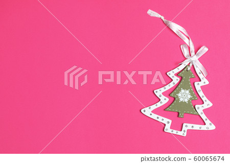 Xmas decorations. Christmas toy white with olive carved wooden Christmas tree on bright pink background. Top view, copy space. Xmas decorations. Christmas toy white with olive carved wooden Christmas tree on bright pink background. Top view, copy space. 60065674