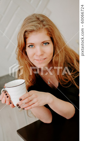 Woman holds a cup of coffee in the morning in Christmas kitchen Woman holds a cup of coffee in the morning in Christmas kitchen 60066724