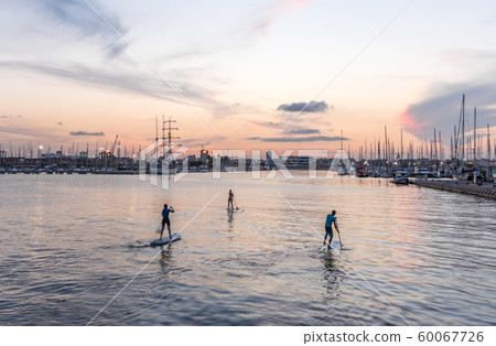Silhouette of stand up paddle boarder paddling at sunset on a flat warm quiet sea Silhouette of stand up paddle boarder paddling at sunset on a flat warm quiet sea 60067726