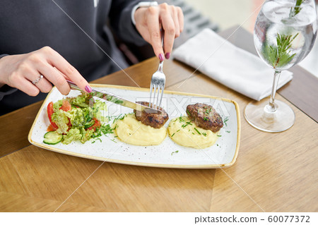 Lunch in a restaurant, a woman eats Delicious juicy meat cutlets, mashed potatoes sprinkled with 60077372