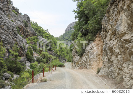 Fenced trail in gorge among mountains covered by green pine forest. Selective focus. 60082015