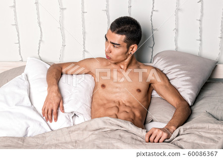 Young handsome man rest in bed. Sexy naked guy is Young handsome man rest in bed. Sexy naked guy is 60086367