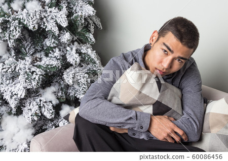 Young happy man sitting on couch near christmas Young happy man sitting on couch near christmas 60086456