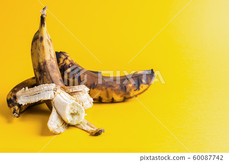 Two overripe blackened ugly bananas on bright yellow background with copy space. Zero waste concept. Two overripe blackened ugly bananas on bright yellow background with copy space. Zero waste concept. 60087742