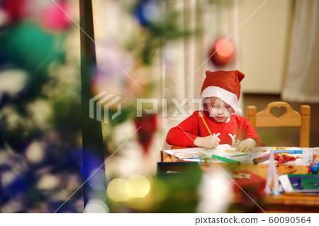Little boy wearing in a Santa costume is drawing Little boy wearing in a Santa costume is drawing 60090564