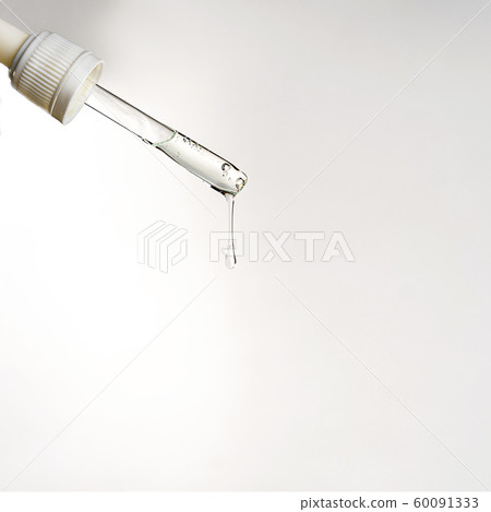 Pipette with drop of serum or hyaluronic acid on gray background. 60091333