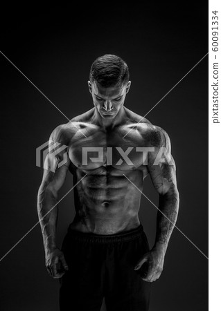 Bodybuilder posing. Fitness muscled man on dark background. 60091334