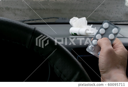 the driver's hand in the car, which holds a package of pills the driver's hand in the car, which holds a package of pills 60095711