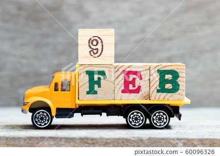 Truck hold letter block in word 9feb on wood background 60096326