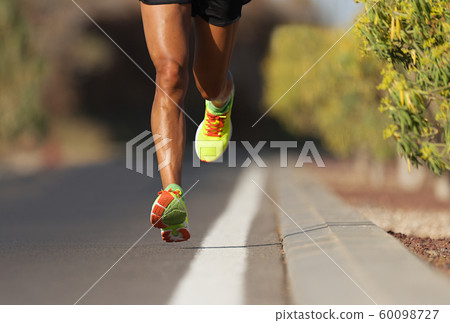 Fast strong runner feet running on asphalt road close up in sport shoe 60098727