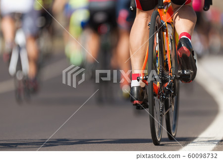 Cycling competition cyclist athletes riding a race at high speed, detail on gear wheels and feet 60098732