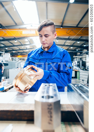 Apprentice in metalworking looking at workpiece 60100603