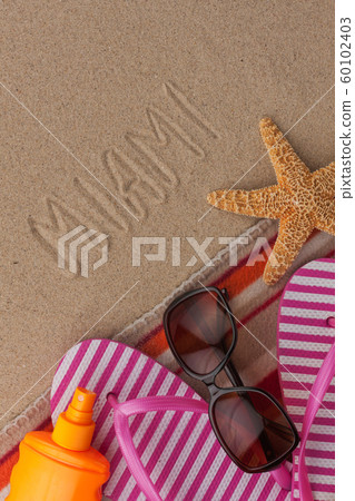 Word MIAMI written in sand with beach accessories. 60102403