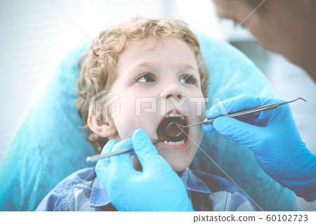 Doctor and patient child. Boy having his teeth examined with dentist. Medicine, health care and stomatology concept Doctor and patient child. Boy having his teeth examined with dentist. Medicine, health care and stomatology concept 60102723