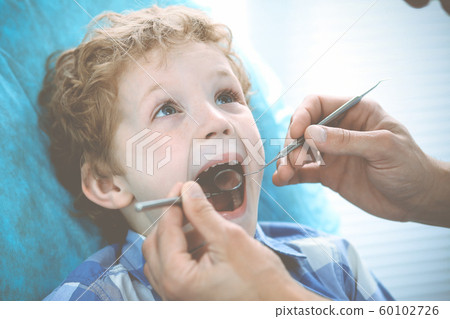 Doctor and patient child. Boy having his teeth examined with dentist. Medicine, health care and stomatology concept Doctor and patient child. Boy having his teeth examined with dentist. Medicine, health care and stomatology concept 60102726
