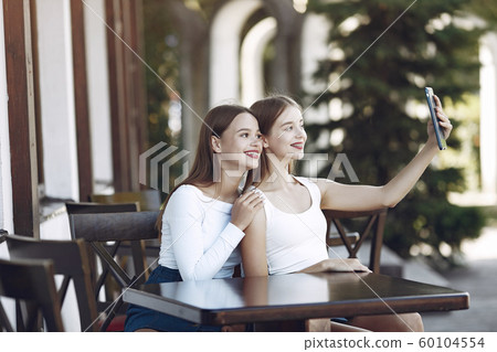 Two elegant and stylish girls in a summer cafe Two elegant and stylish girls in a summer cafe 60104554