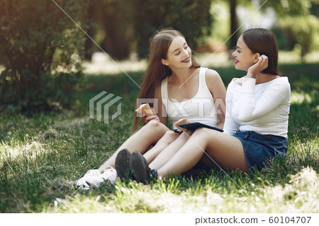 Two elegant and stylish girls in a spring park Two elegant and stylish girls in a spring park 60104707