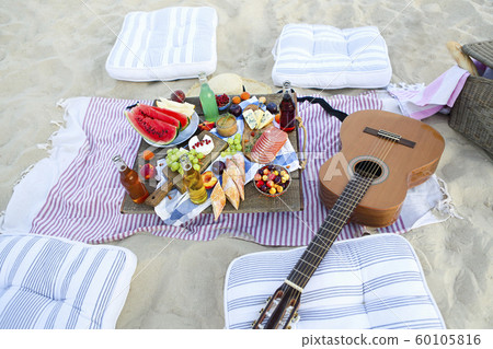 Picnic on the beach at sunset in the style of boho 60105816