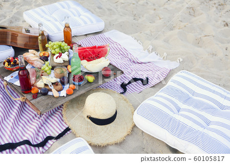 Picnic on the beach at sunset in the style of boho 60105817