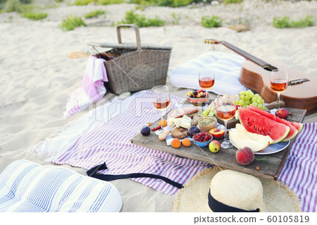 Picnic on the beach at sunset in the style of boho 60105819