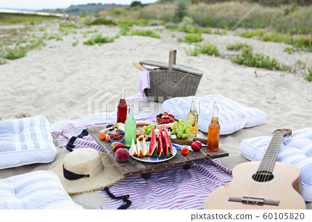 Picnic on the beach at sunset in the style of boho 60105820