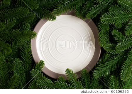 Top view of white plate surrounded with fir tree Top view of white plate surrounded with fir tree 60106255