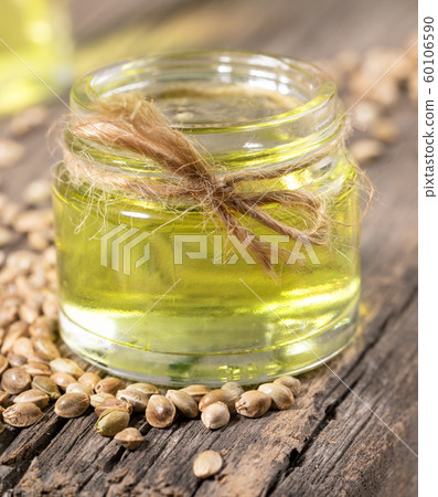 Hemp CBD oil in glass jar and grains of cannabis on background of old wooden boards close-up. Natural products concept. 60106590