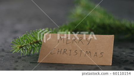 merry christmas card next to spruce twig 60110154