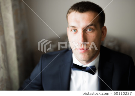 Grooms morning preparation. Handsome man getting dressed and preparing for the wedding 60110227