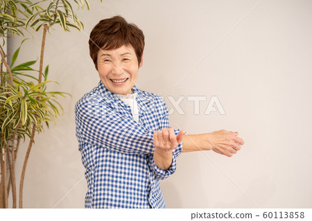 Senior woman stretching second arm Senior woman stretching second arm 60113858