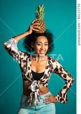 Playful young african american woman with fresh pineapple on head as crown. Healthy exotic lifestyle and eating concept. Playful young african american woman with fresh pineapple on head as crown. Healthy exotic lifestyle and eating concept. 60115750