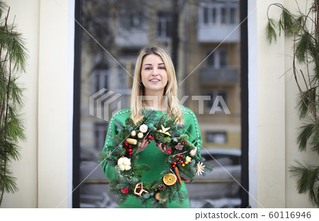 Girl holding Christmas wreath maked by herself 60116946
